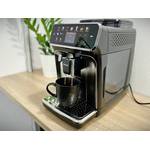 Der Philips Series 5400 (EP5447/90) Kaffeevollautomat bereitet gerade frischen Kaffee zu. Der Auslauf füllt eine schwarze Tasse auf der Abtropffläche.