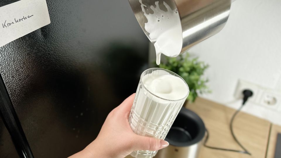 Milchschaum wird aus dem WMF Lono Milk & Choc in ein Glas gegossen. Die Bewegung ist eingefroren in einem mittleren Strahl.