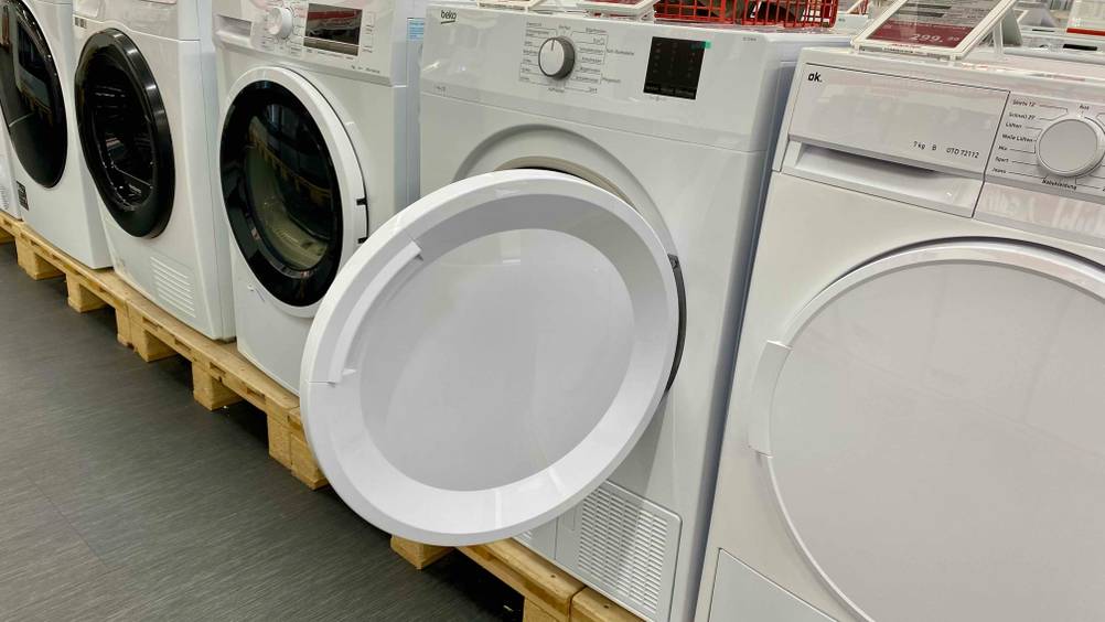 Beko-Trockner-Test: Ein Gerät zwischen anderen auf einem Sockel mit geöffneter Klappe.