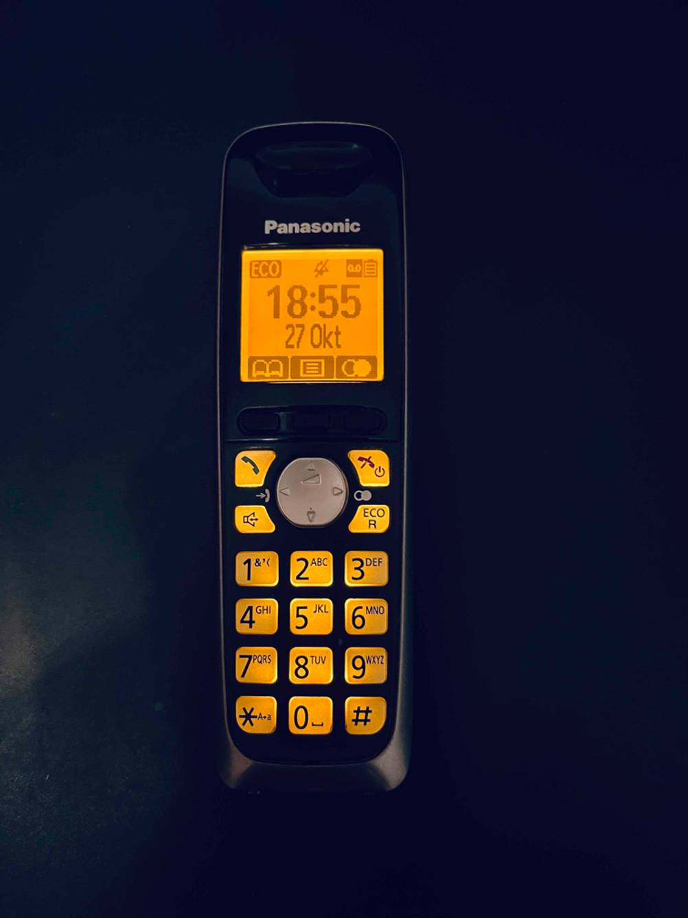 Beleuchtetes, schnurloses Panasonic Telefon befindet sich in Dunkelheit, entfernt von der Telefonanlage im Test.