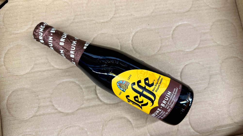 Belgisches Bier-Test: Eine Flasche leicht horizontal auf einem Karton liegend.