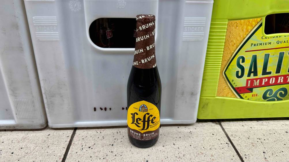 Belgisches Bier getestet: Eine Flasche steht vor einem Getränkekasten auf dem Boden.