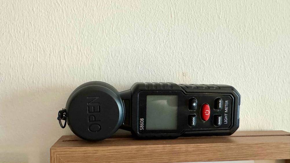 Getestet: Ein Belichtungsmesser liegt horizontal auf einem Holzregal.