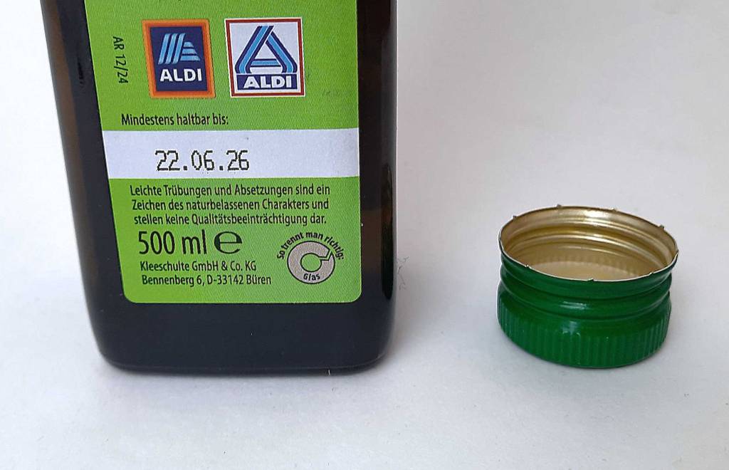 Auf der Rückseite einer Flasche getestetes Speiseöl stehen Informationen zum Inhalt, der Verschluss liegt daneben.