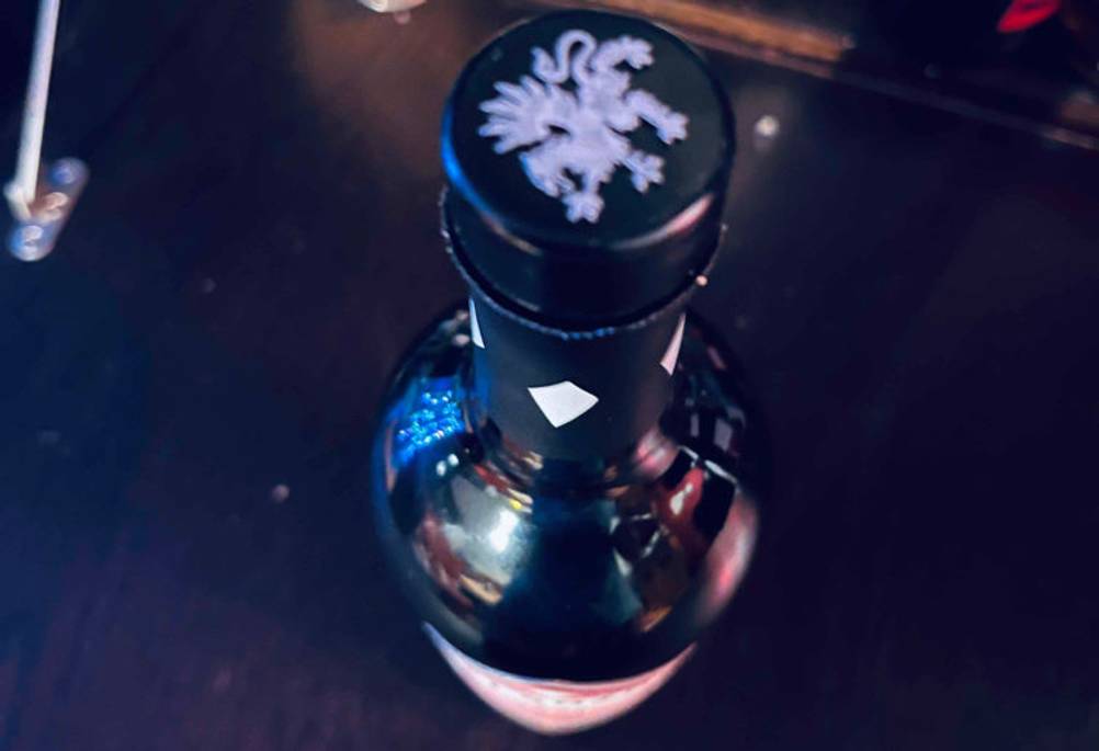 Blickdichte Flasche Vermouth im Test, mit Fokus auf den mit Kunststoff überzogenen Naturkorken vor dunklem Hintergrund.