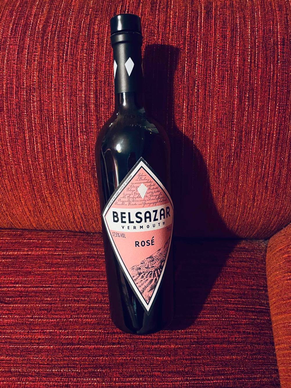 Eine dunkle Flasche Belsazar Rosé Vermouth im Test auf rotem Stoff.