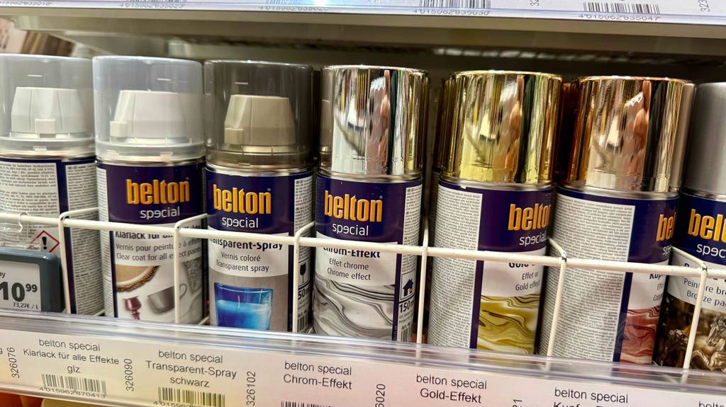 Chrom-Spray im Test: Mehrere Dosen stehen zwischen anderen Farben in einem Regal.