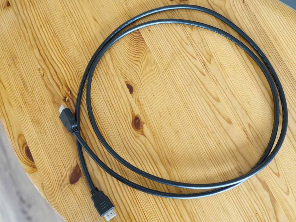 Gesamtansicht von oben auf ein schwarzes HDMI-2.1-Kabel im Test, das auf einem Holztisch liegt.