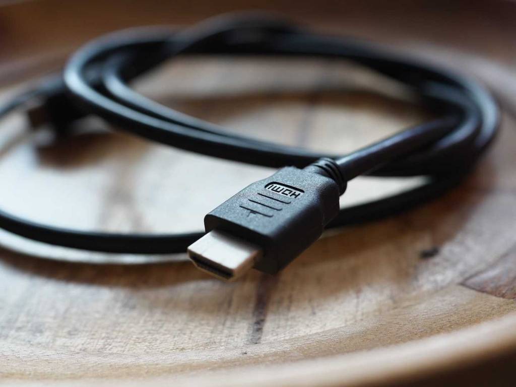 HDMI-2.1-Kabel im Test: Nahaufnahme des Anschlusses eines schwarzen, langen Kabels auf einem Holztisch.