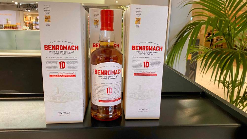 Single-Malt-Scotch-Whisky getestet: Eine Flasche von vorne zwischen zwei Originalkartons auf einer dunklen Fläche in einem Verkaufsraum.