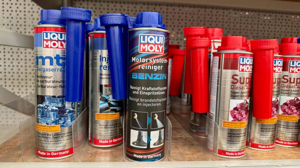 Mehrere Dosen des getesteten Benzin-Additivs neben anderen Produkten im Regal.