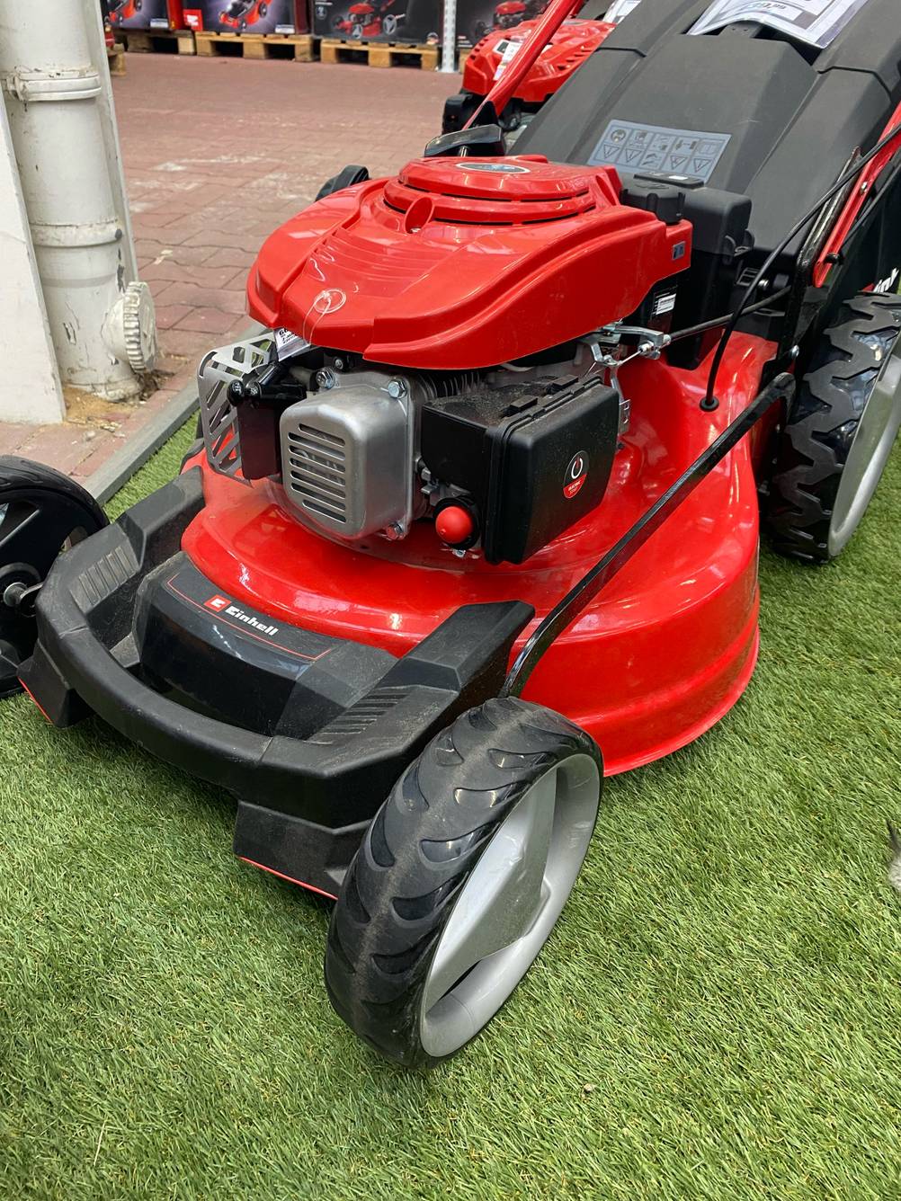Nahaufnahme des Motors eines getesteten Benzin-Rasenmäher mit 51 Zentimetern Schnittbreite von schräg vorne auf einem Kunstrasen.