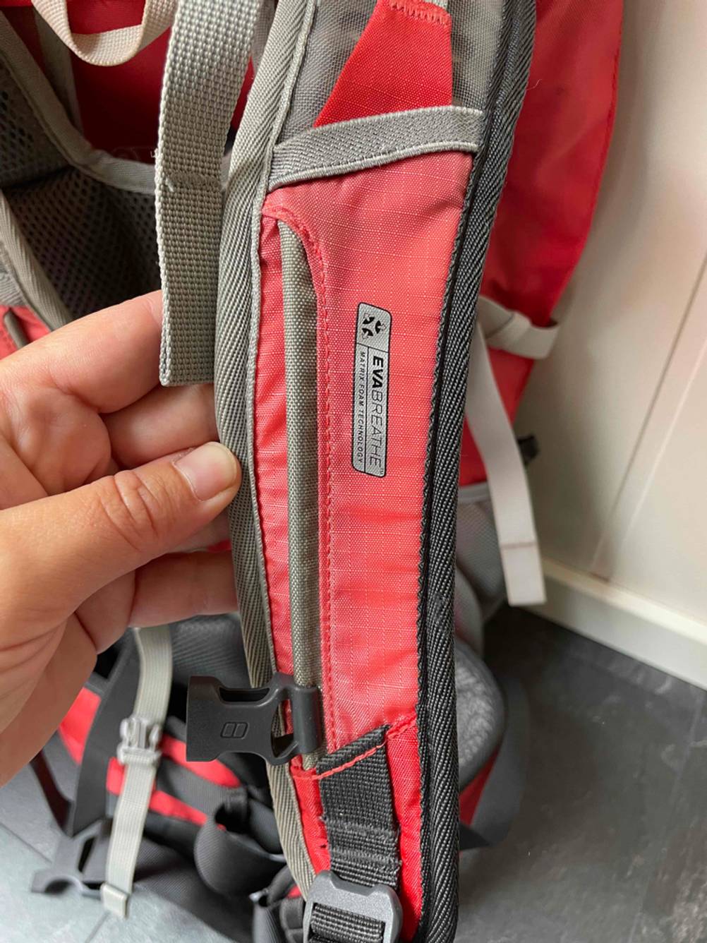 Damen-Wanderrucksack-Test: Eine Hand zeigt ein Materialdetail des Trägergurts eines Wanderrucksacks für Damen.