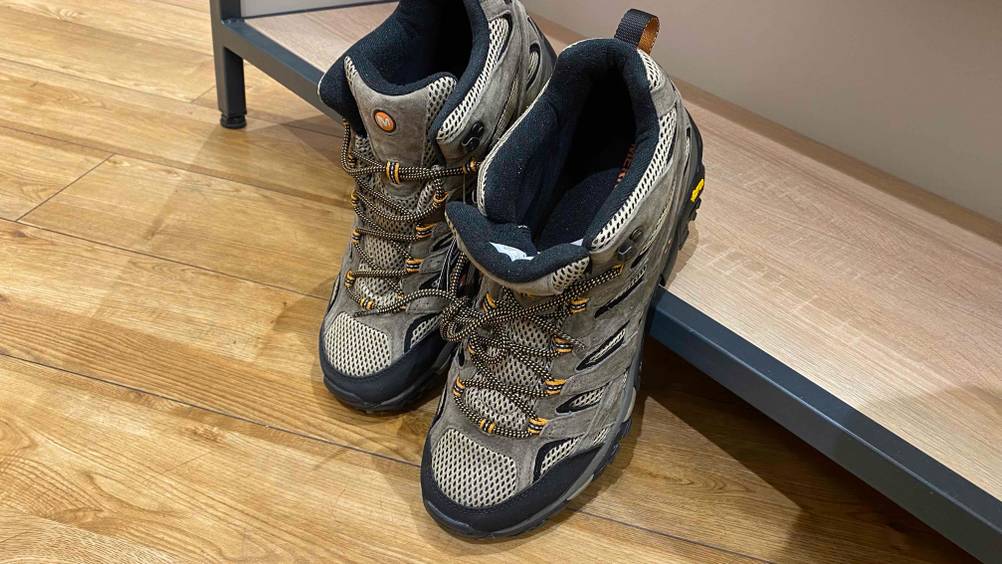 Bergschuhe für Herren getestet: Bergschuhe von Merrell lehnen an einem Regalbrett.