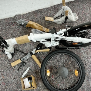 Zu sehen ist der teilweise verpackte Lieferumfang des Bergsteiger Windsor mit demontiertem Vorderrad und Zubehörteilen auf einer Decke.