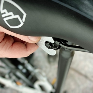 Die Sattelklemmung des Bergsteiger Windsor wird in der Nahaufnahme gezeigt. Eine Hand greift zum Montageschlüssel an der Unterseite des Sattels.