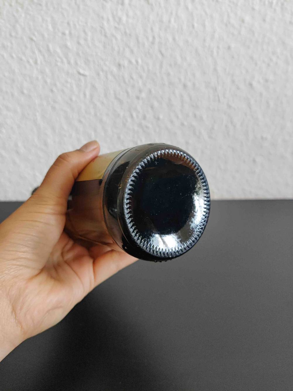 Im Test: Nahaufnahme des Bodens einer Flasche Bier die eine Hand hält.