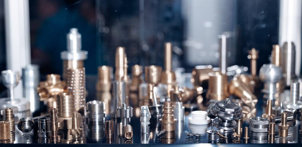 Bernardo-Drehmaschine im Test: Drehteile verschiedenster Art aus diversen Materialien stehen auf einer Fläche.