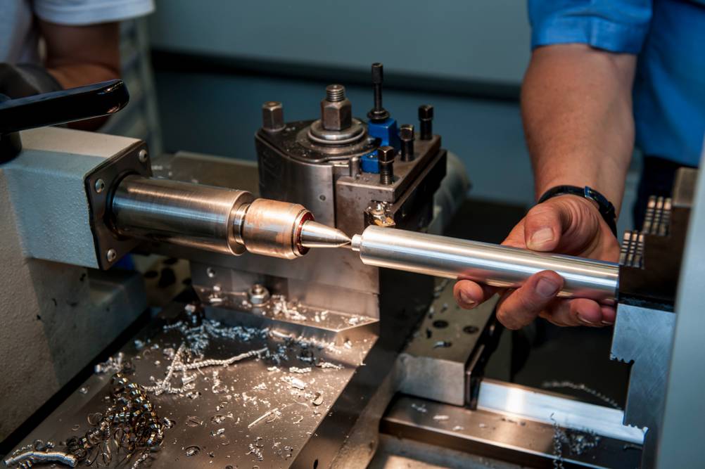 Bernardo-Drehmaschine im Test: Eine Hand hält ein Drehteil in der Maschine – vermutlich Einspannen oder Herausnehmen.