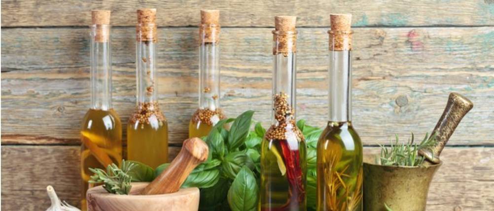 Bertolli-Olivenöl-Test: Vor einer Holzwand stehen diverse Glasflaschen mit Öl. 