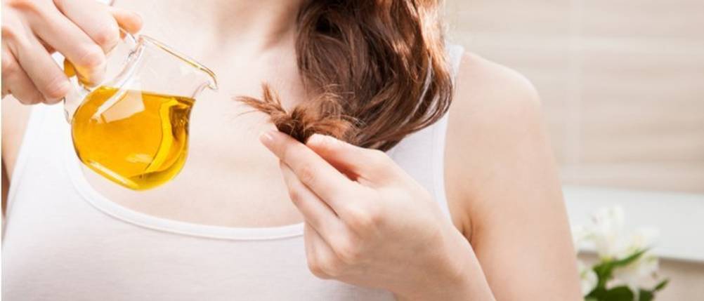 Bertolli-Olivenöl-Test: Eine Frau hält eine kleine Glaskanne mit Olivenöl in der Hand und träufelt dieses über ihre Haarspitzen. 