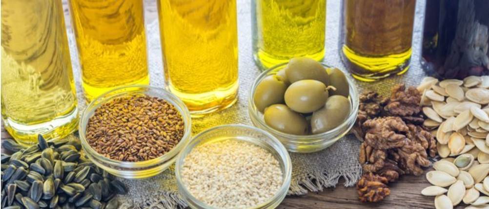 Bertolli-Olivenöl-Test: Diverse Glasflaschen mit Öl und kleine Schälchen mit Samen und Oliven stehen nebeneinander. 