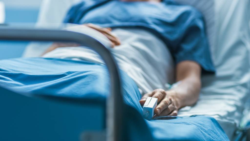 Eine Person liegt in einem Krankenhausbett.