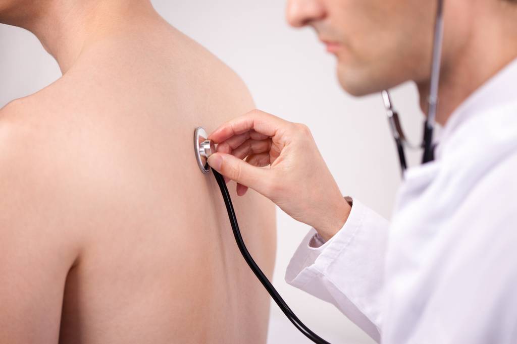 Ein Arzt untersucht einen Patienten mit einem Stethoskop.