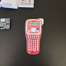 Ein rotes Brother-Beschriftungsgerät liegt auf einem Schreibtisch.