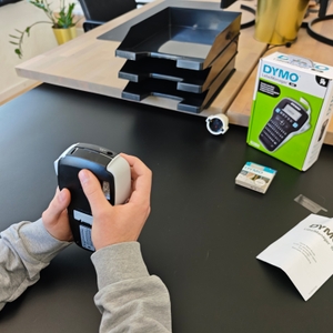 Ein Dymo LabelManager 160 wird in der Hand gehalten.