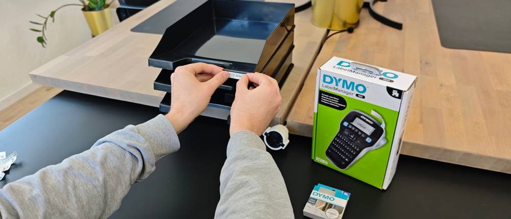 Ein gedrucktes Label wird auf ein Ablagefach geklebt.