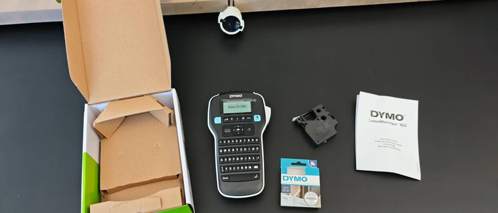 Ein Dymo Labelmaker 160 liegt samt seiner Verpackung auf einem Tisch.