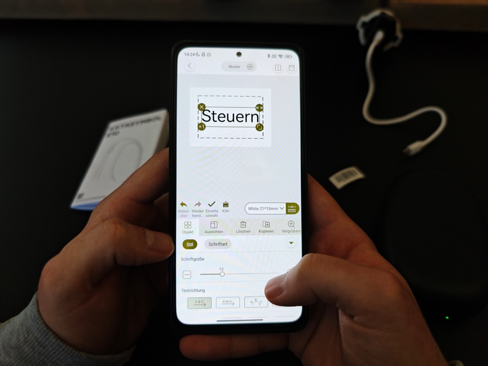 Auf einem Handy wird in einer Labeldrucker-App das Wort 