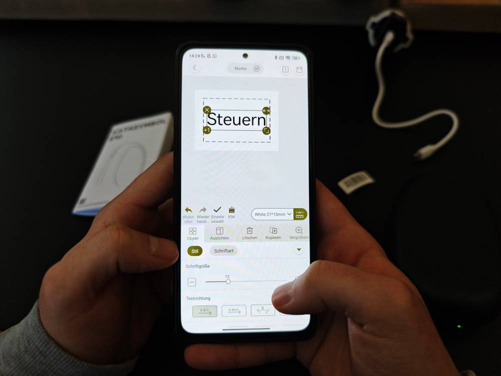 Auf einem Handy wird in einer Labeldrucker-App das Wort 