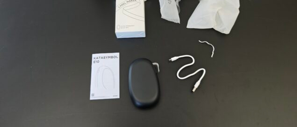 Ein Supvan-Beschriftungsgerät liegt samt Zubehör auf einem Tisch.