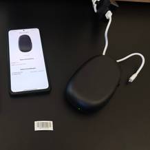 Der Supvan E10 liegt neben einem Handy und der Anleitung auf einem schwarzen Tisch.