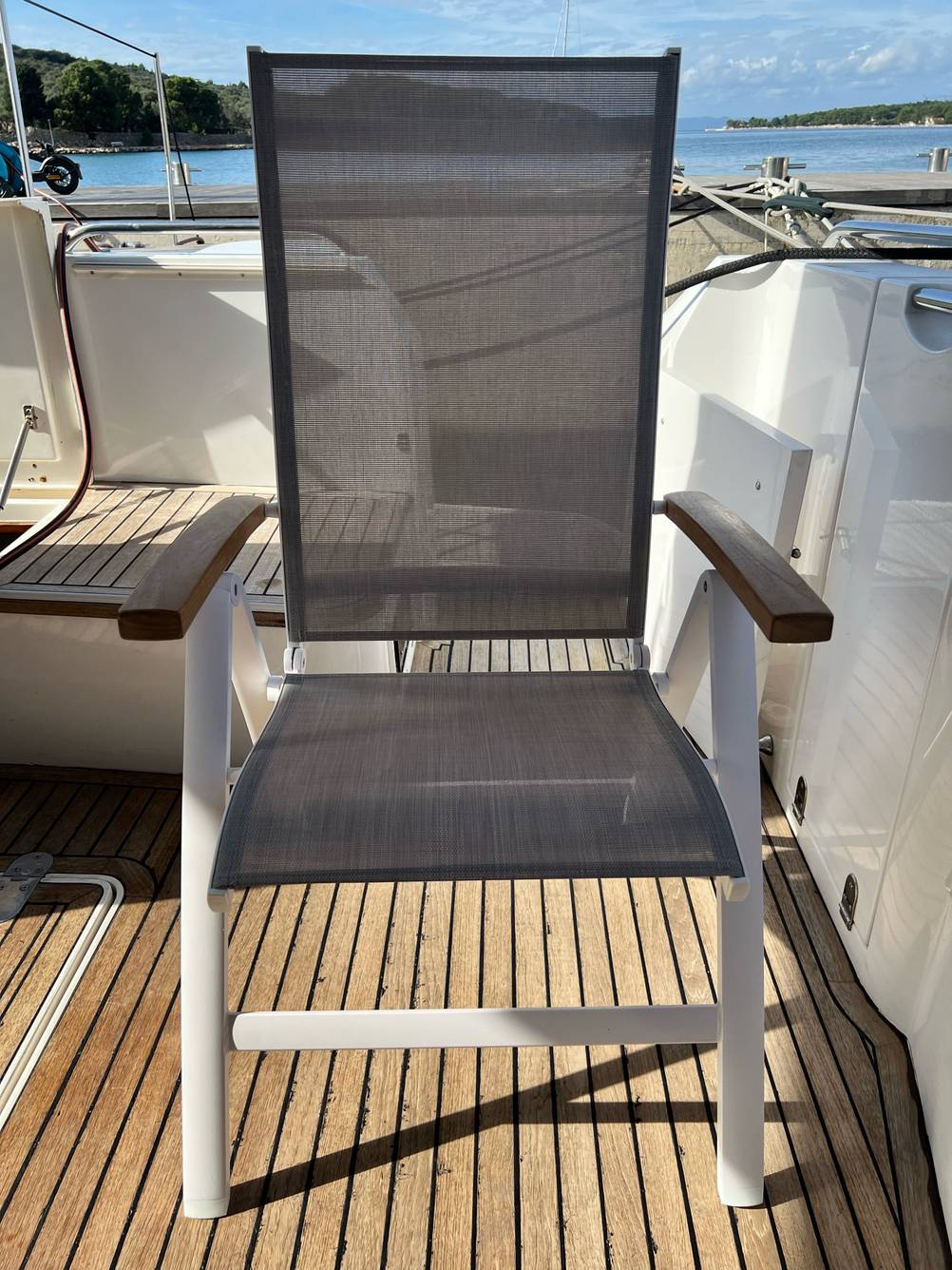 Ansicht eines mit grauem Netzstoff bespannten Campingstuhl bis 150 kg im Test, der auf einem Boot platziert ist.