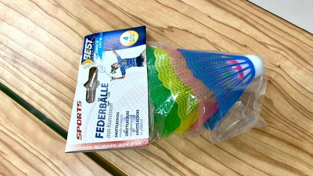Bunte Best-Sports Badminton-Bälle im Test liegen in Zellophan verpackt auf einer Holzfläche.