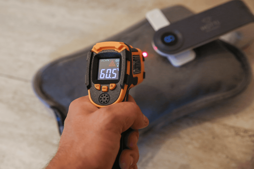 Test elektrischer Wärmflaschen: Eine Person misst mit einem Laser-Thermometer die Temperatur einer Wärmflasche.