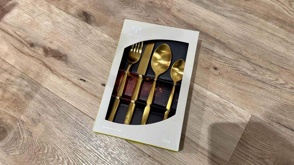 Auf einer Holzfläche liegt eine Packung des getesteten Besteck gold.