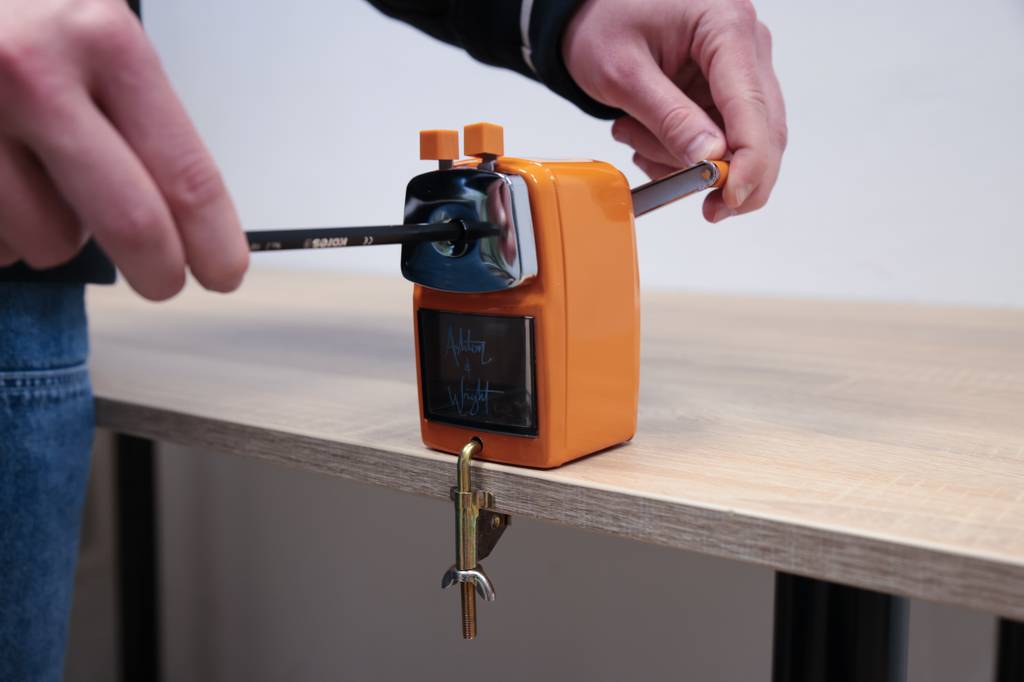 Anspitzer-mit-Kurbel-Test: Bleistift wird in orangenem Anspitzer mit Kurbel, der am Tisch befestigt wird, angespitzt.
