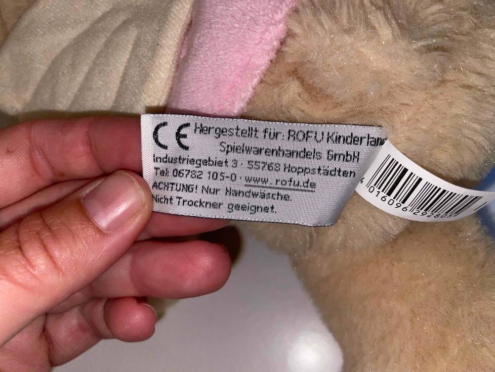 Hand hält Produkt- sowie Pflegeetikett eines getesteten Kuscheltiers der Marke Besttoy.