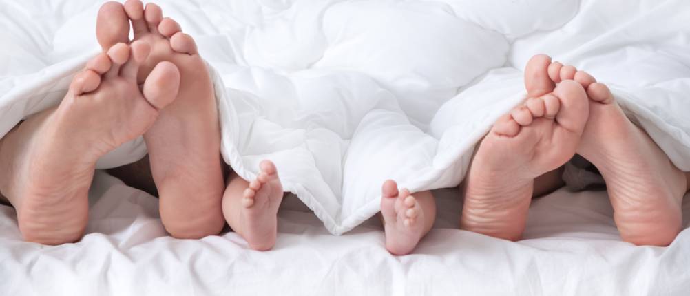Couple with baby showing foot under the blanket