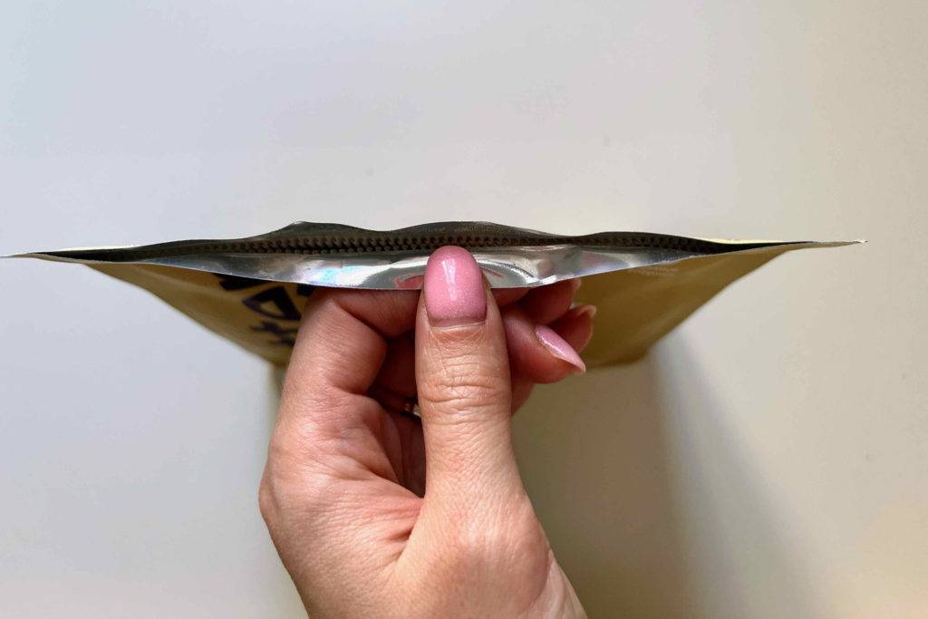 Eine Hand öffnet eine Packung Erbsenprotein-Pulver zum testen.