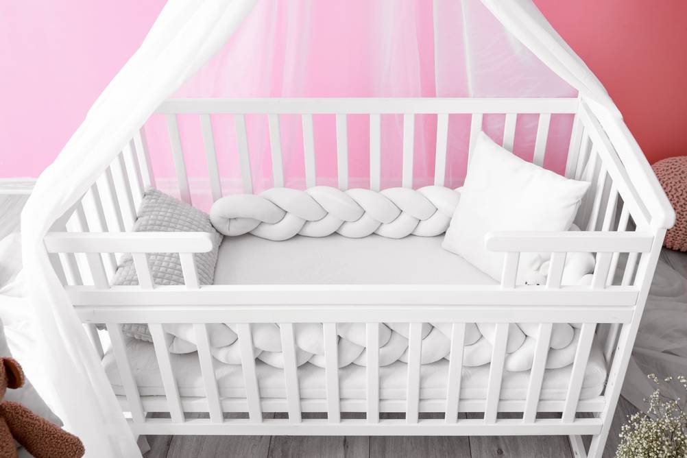 Bettschlange-Test: Eine geflochtene Bettschlange liegt in einem Kinderbett.