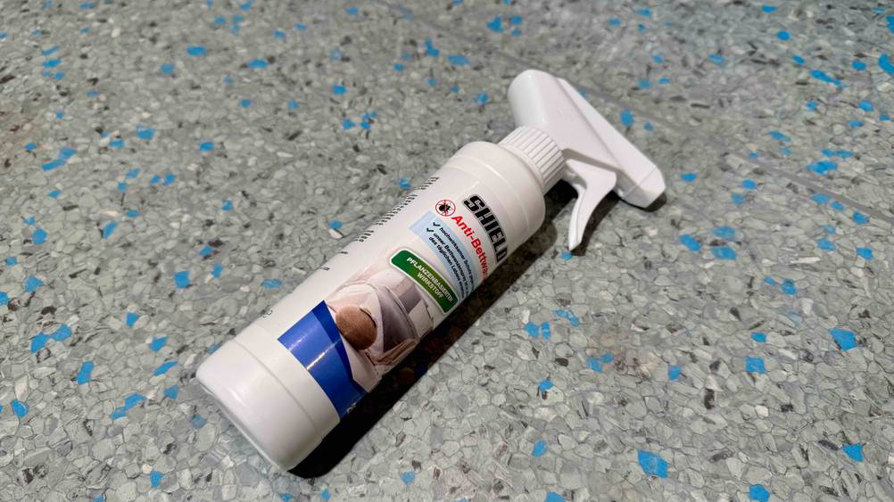 Eine Flasche des Bettwanzensprays liegt auf einem grau-blauen Boden.