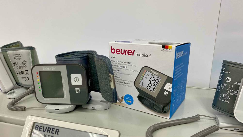 Blutdruckmessgerät getestet: Ein Gerät neben seiner Originalverpackung auf einem Verkaufsregal zwischen anderen Produkten.