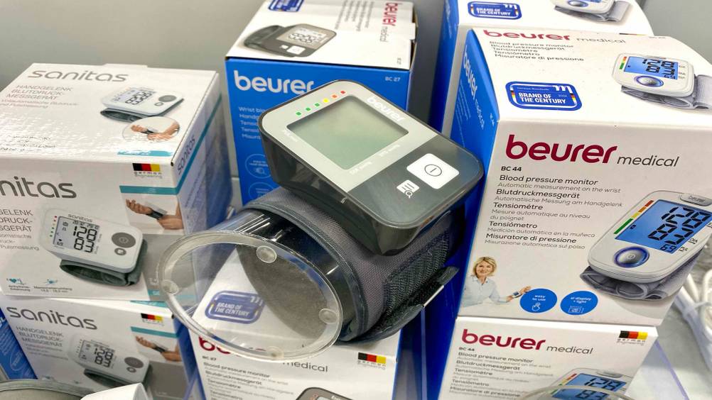 Beurer-Blutdruckmessgerät getestet: Ein Gerät an einer transparenten Rolle befestigt zwischen Originalverpackungen liegend.