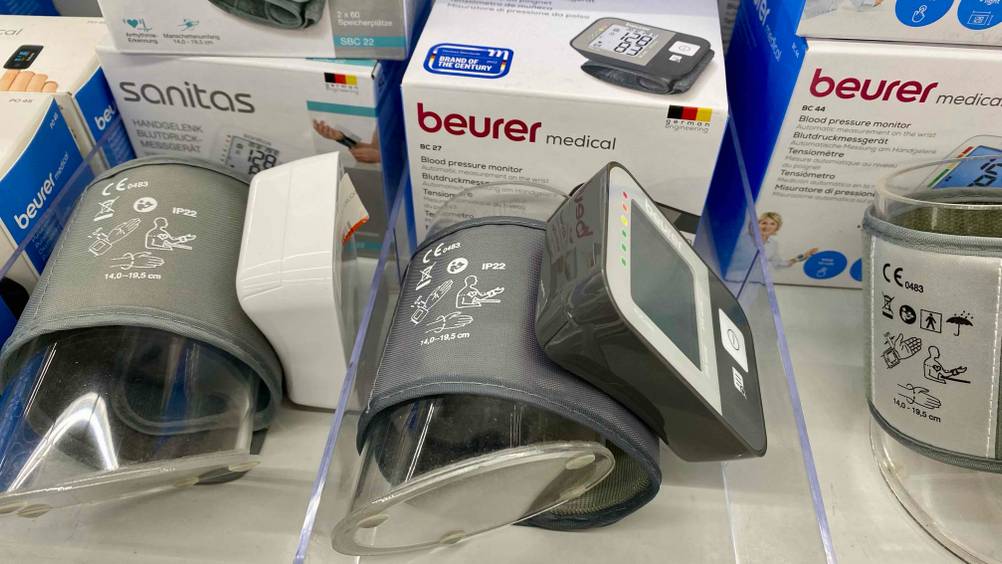 Ein Beurer-Blutdruckmessgerät im Test von der Seite an einer transparenten Rolle befestigt.