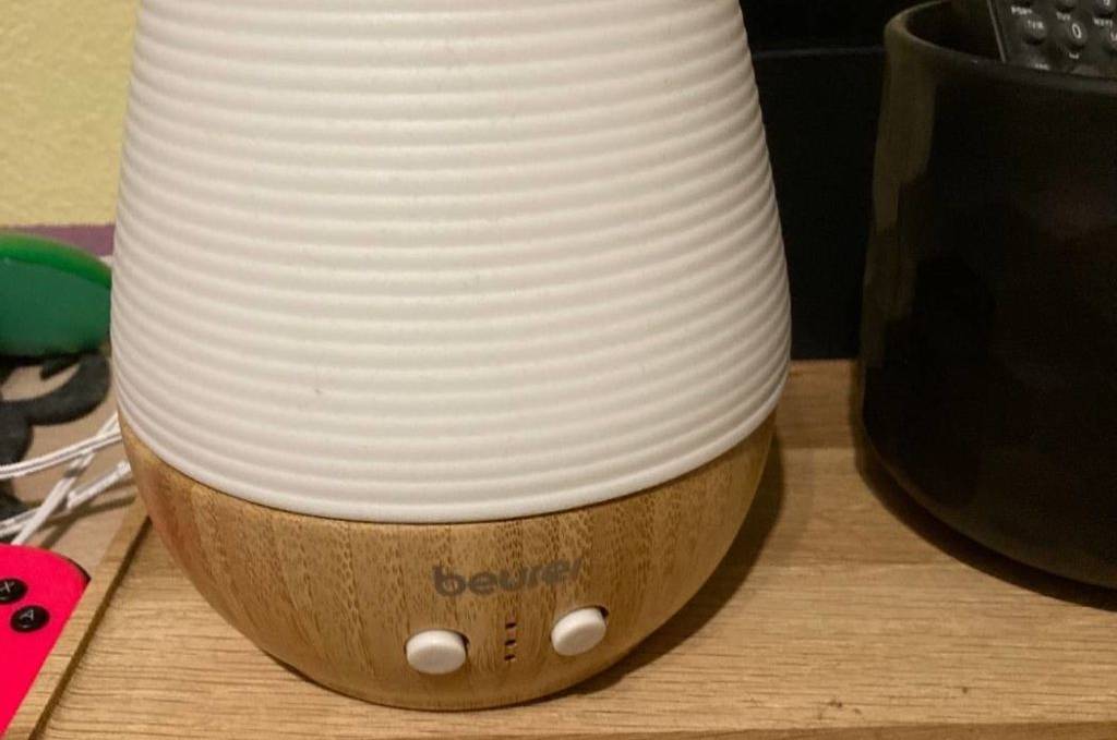 Elektrischer Beurer LA 40 Diffuser im Test steht auf einer Holzfläche. Das Modell verfügt über eine Holzbasis und einen weißen Lampenschirm.